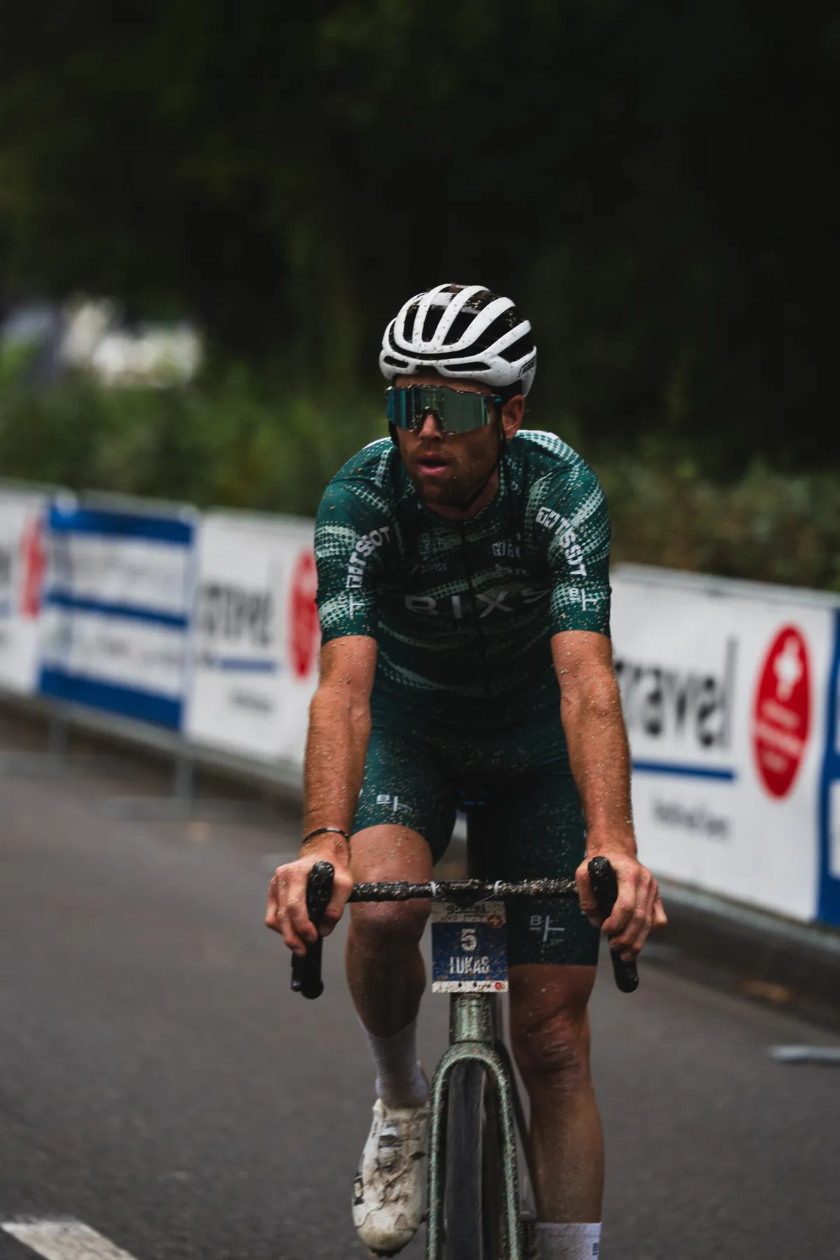 BIXS-Fahrer mit Startnummer 5 rollt mit dreckverspritztem Trikot allein über die Zielgerade entlang der Sponsorenbanden