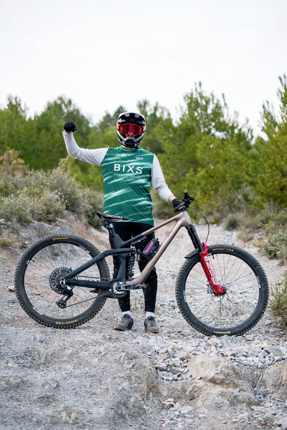 BIXS Enduro-Mountainbike in Roségold, Fahrer jubelt auf Schotterpiste