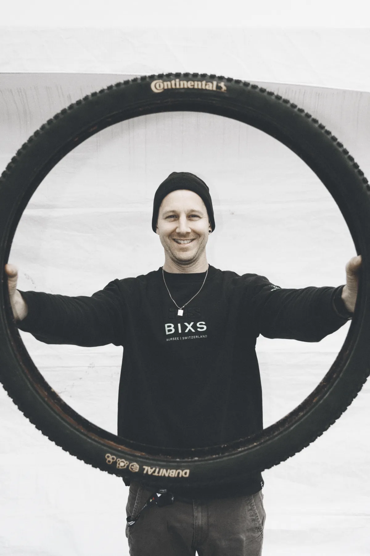 Severin Saegesser, Mechaniker im BIXS Race Team, lächelt durch einen Reifen in die Kamera