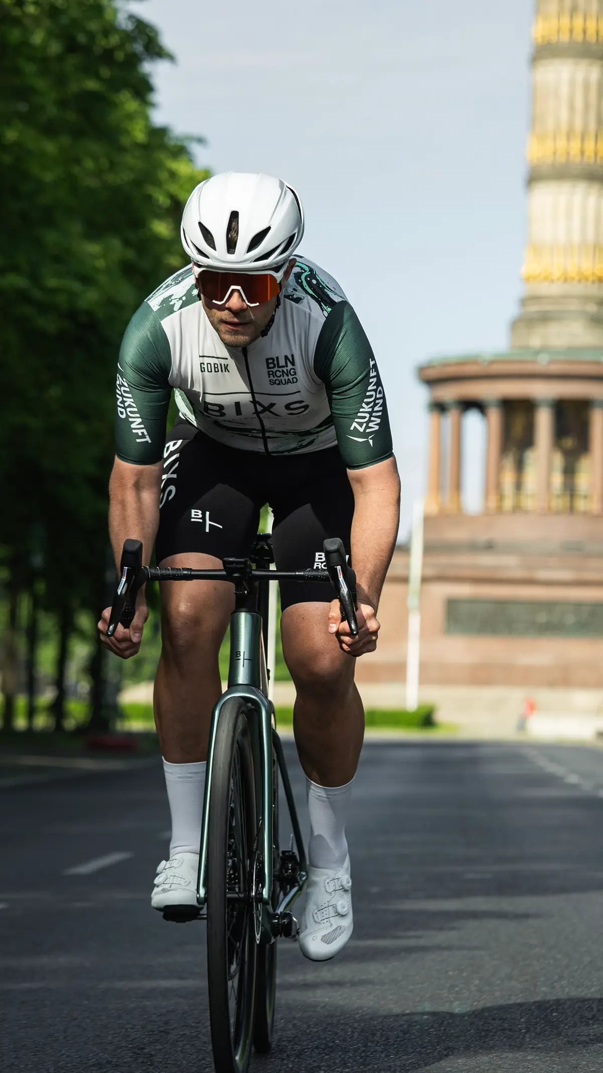 Fahrer im Teamtrikot fährt auf Fahrer zu, Berliner Siegessäule im Hintergrund