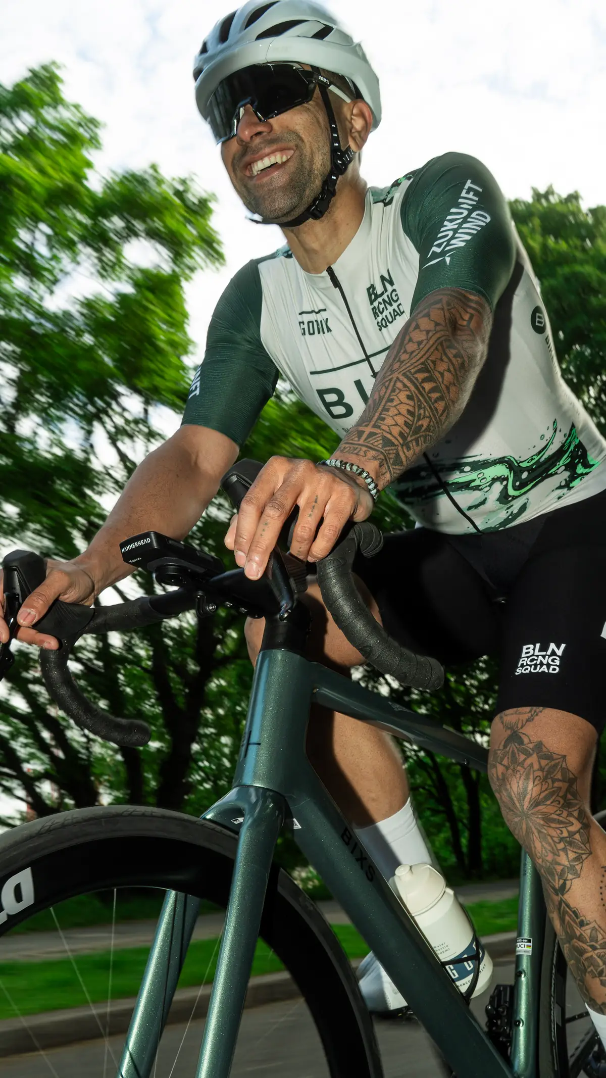Lächelnder Fahrer mit Tattoos im Teamtrikot aus der Froschperspektive