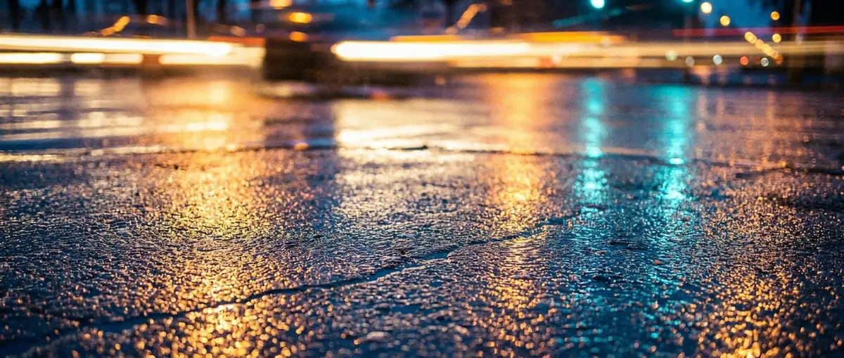 Nasser Asphalt mit Lichtreflexionen bei Nacht als Hintergrundtextur für E-Urban