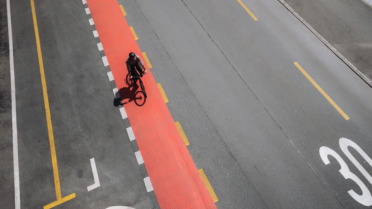 Luftaufnahme eines Fahrers auf BIXS Urban-Bike auf rotem Velostreifen in der Stadt