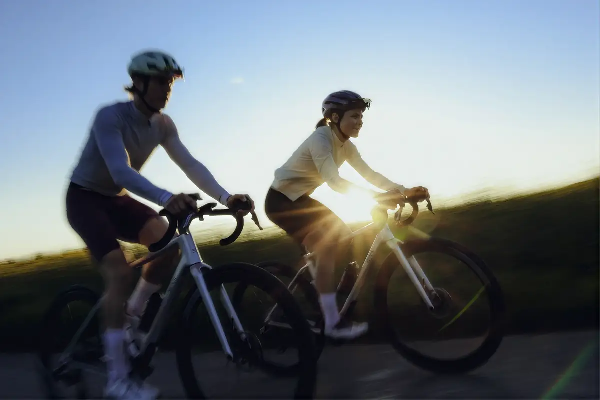 Zwei Rennradfahrer im Gegenlicht der tiefstehenden Sonne, dynamische Bewegungsunschärfe