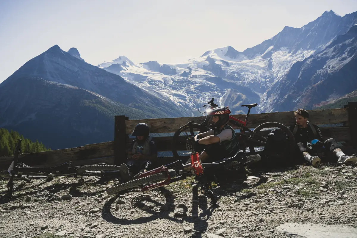 Enduro-Fahrer machen Pause an einem Holzzaun vor einem Gletscher