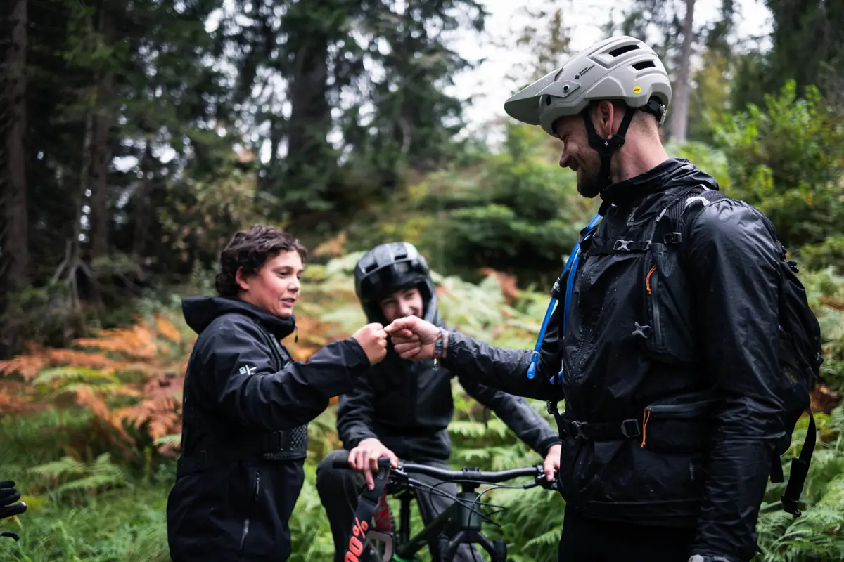 Kinder der BIXS Traction Crew geben sich mit einem Erwachsenen die Faust im Wald