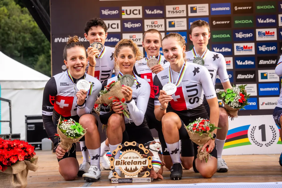 Sechs Fahrerinnen und Fahrer des Schweizer Nationalteams zeigen ihre WM-Medaillen auf dem Podest in Val di Sole