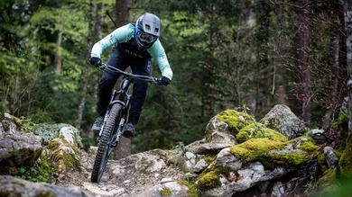 BIXS Fahrer im Mint-Schwarz-Kit springt mit dem Lane über felsigen Waldtrail