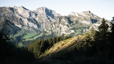 Zwei Fahrer mit BIXS Peak Enduro-Bikes auf Bergtrail vor massivem Alpenpanorama