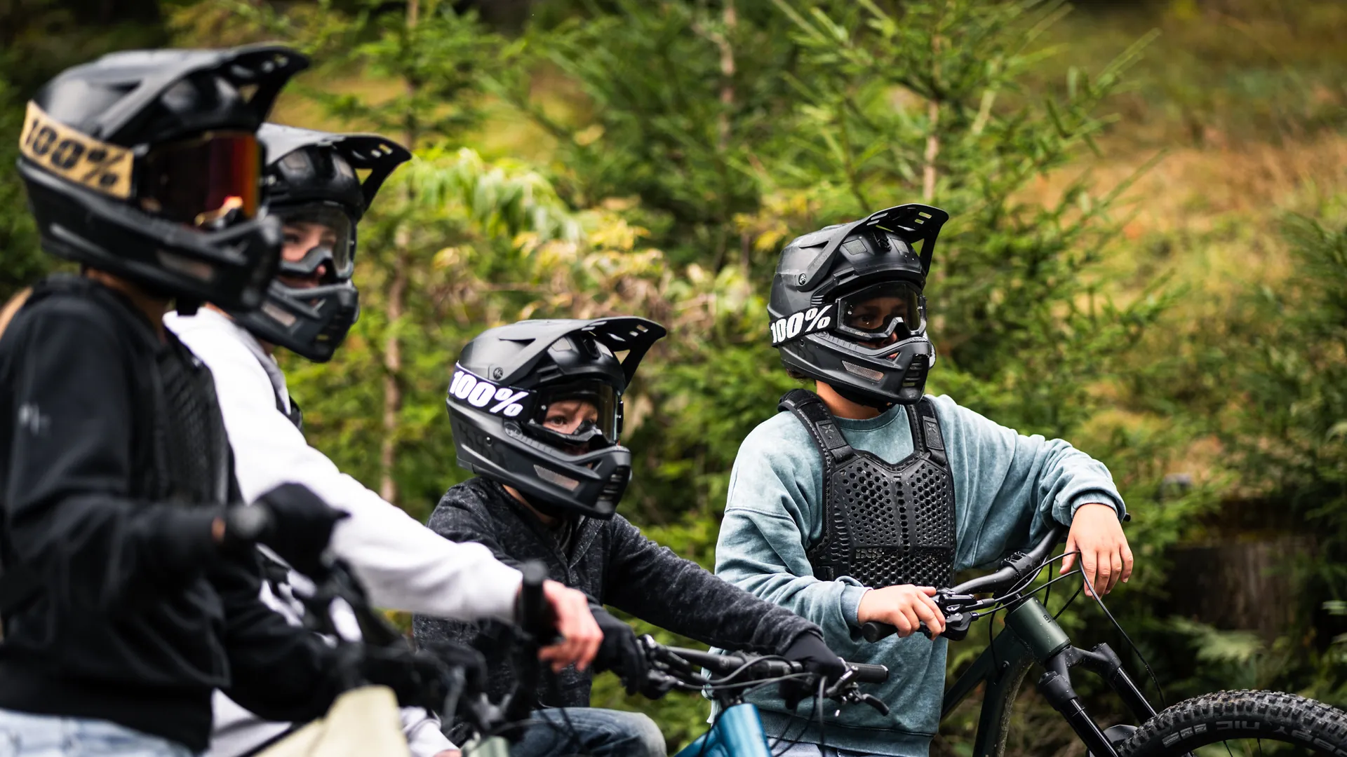 Jugendliche der BIXS Traction Crew mit Fullface-Helmen und Protektoren im Wald