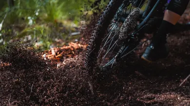 Nahaufnahme des Hinterrads eines BIXS Hardtail-Mountainbikes, das durch Schlamm spritzt