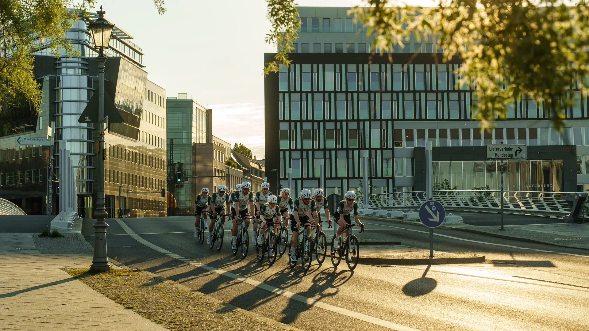Rennradgruppe im Teamtrikot fährt durch Berliner Strasse im Abendlicht