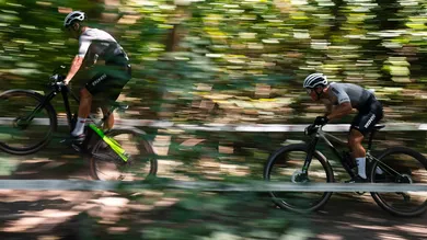Zwei Rennfahrer mit BIXS Core Hardtails rasen mit starker Bewegungsunschärfe durch einen Waldabschnitt