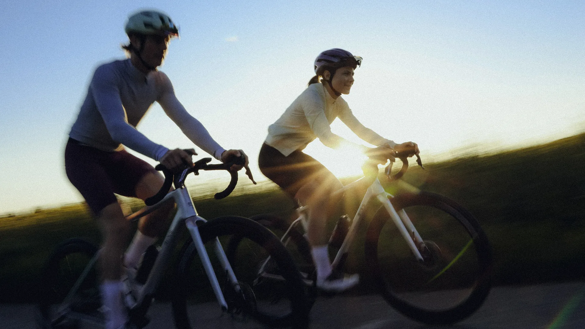 Zwei Rennradfahrer fahren im Gegenlicht der Abendsonne nebeneinander