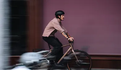 Fahrer mit Tattoos auf E-Bike in Bewegungsunschärfe vor Bordeauxroter Wand