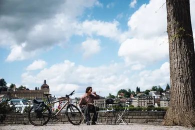 Mann macht Kaffeepause an Bistrotisch neben BIXS Urban Bike mit Blick auf Luzerner Altstadt