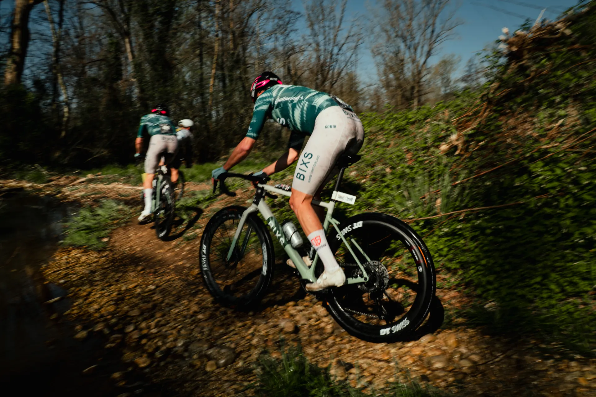 BIXS Race Team Gravelfahrer in dynamischer Fahrt durch herbstlichen Wald