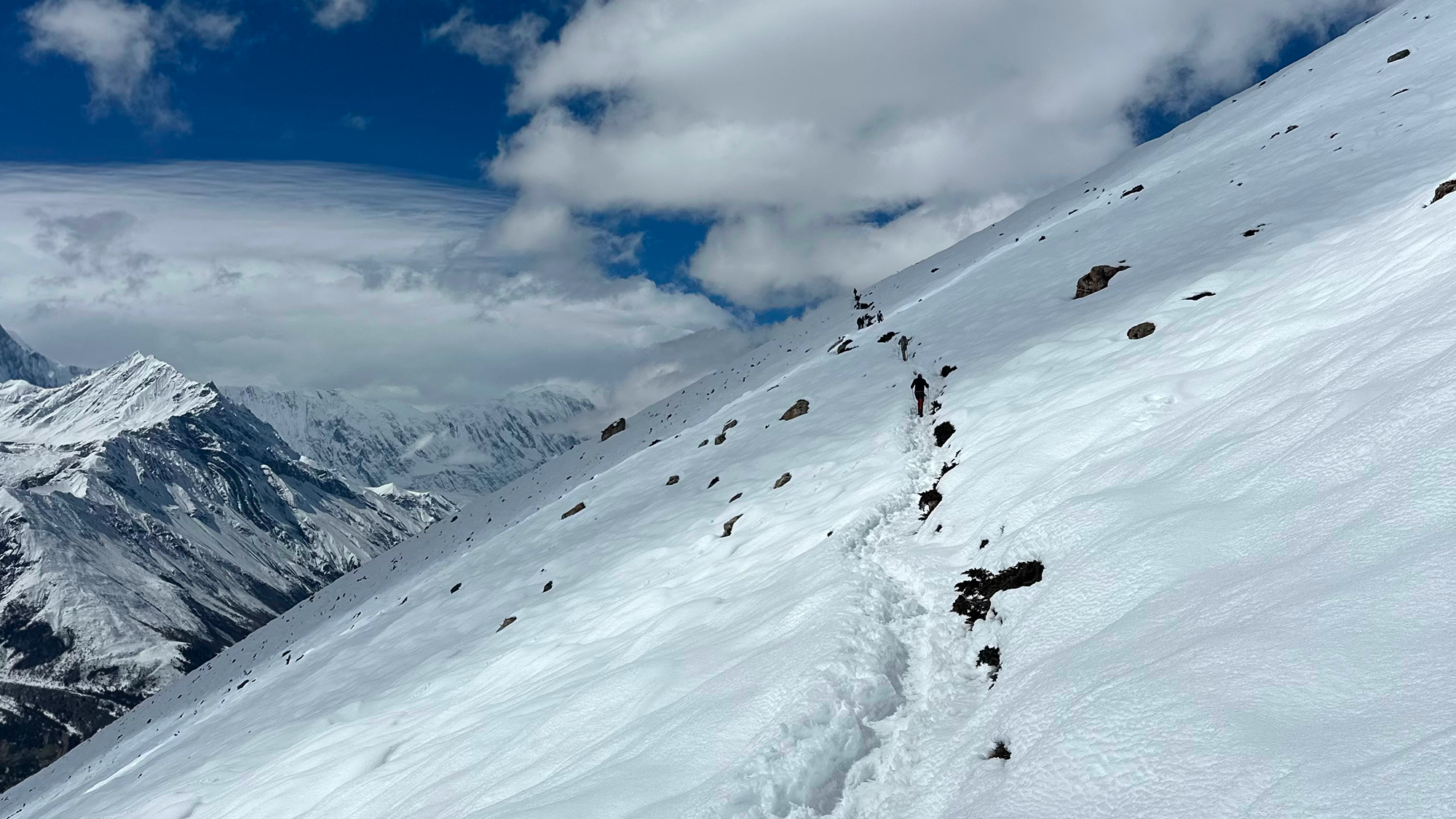 Verschneites Gebirge mit Fussspuren im Schnee.