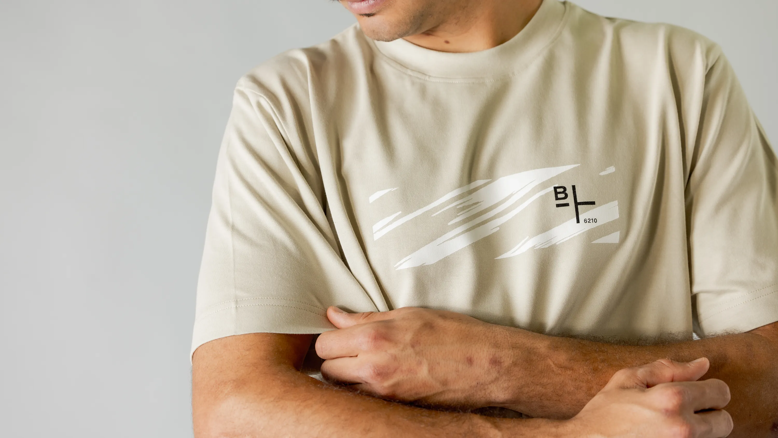 Detailaufnahme von Ärmel und BIXS Logo an beigem T-Shirt am Oberkörper