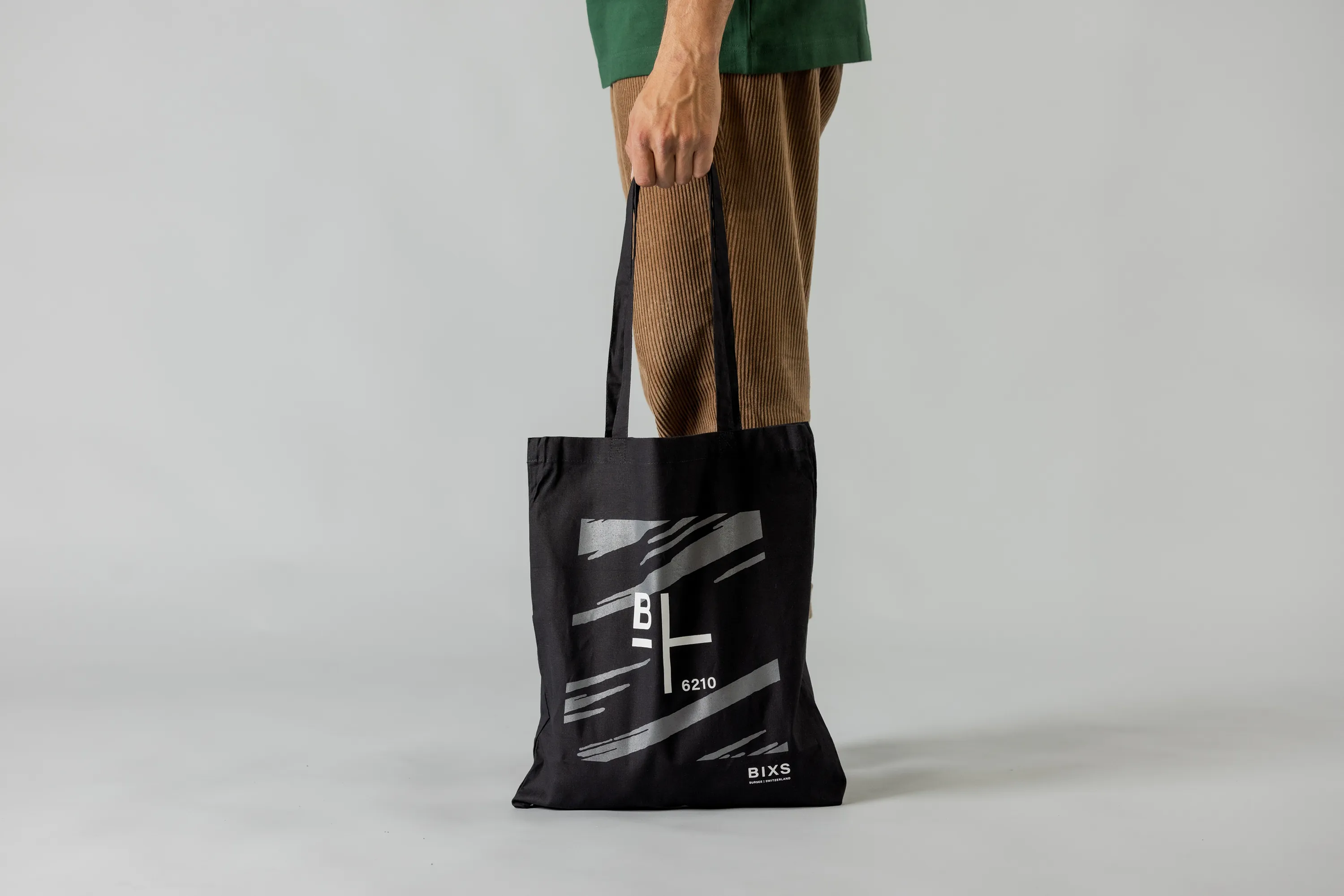 Schwarze BIXS Tragetasche mit Logo-Print, von einer Person am Arm getragen
