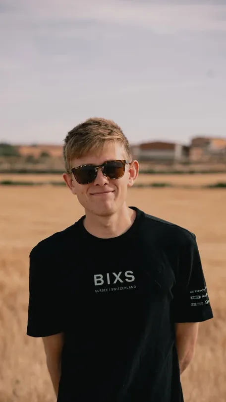 Gian Schmid, Road Manager BIXS Gravel Team, lächelndes Portrait vor Getreidefeld