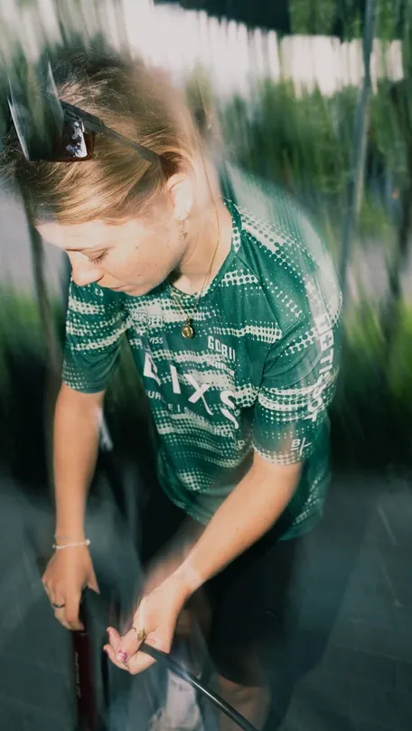 Céline Heuberger, Mechanikerin BIXS Gravel Team, im grünen BIXS Trikot bei der Arbeit am Bike