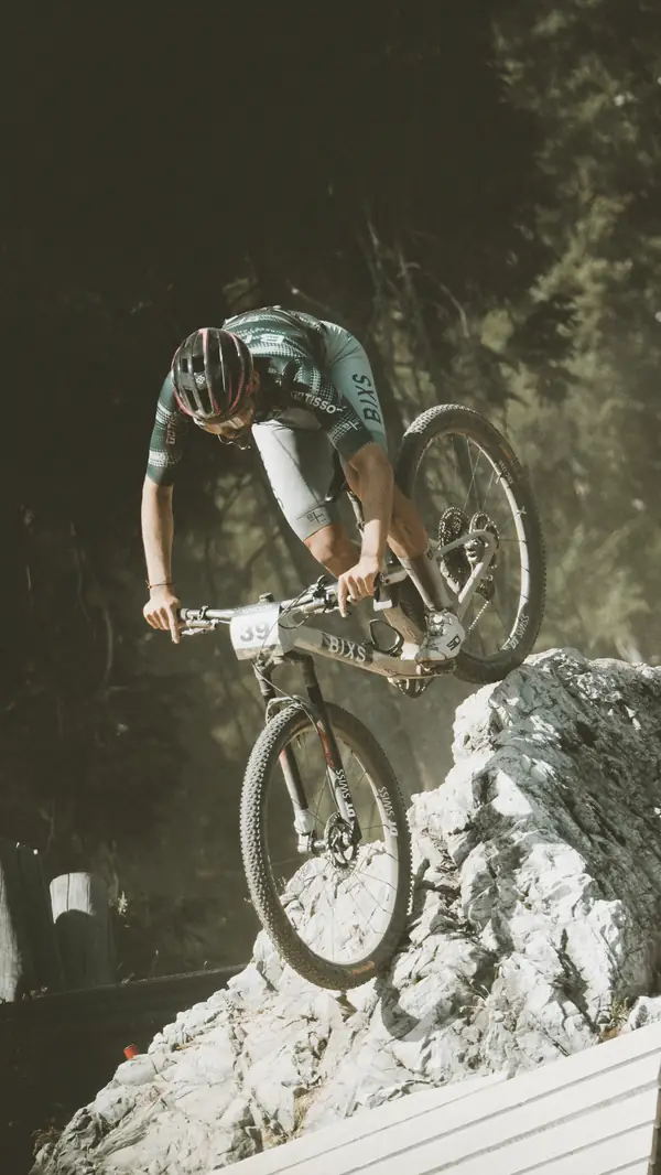 BIXS Race Team Fahrer im Renntrikot springt mit dem Cross-Country-Bike über einen Felsen