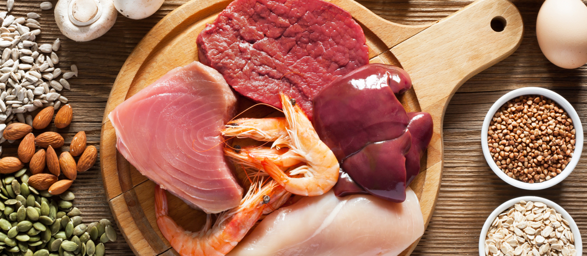 Eier, Leber, Fleisch und Fisch von oben auf grauem Hintergrund.