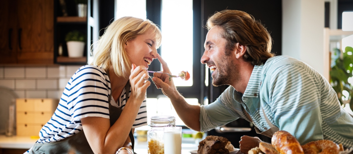 Mann und Frau sitzen an einem Tisch mit Essen und albern herum.