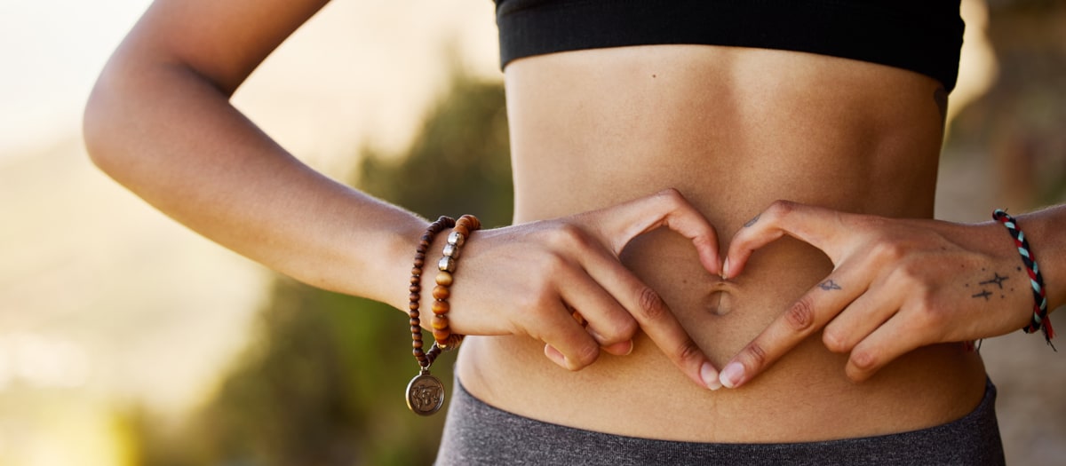 Frau formt Hände vor dem Bauch zu einem Herz.
