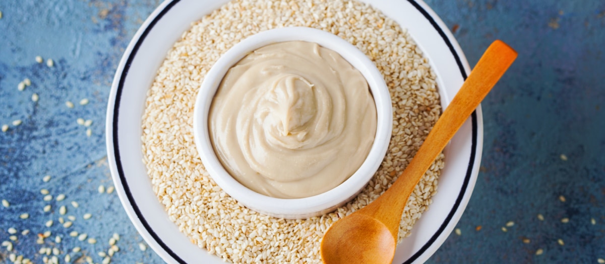 Sesamkörner und cremiges Tahin auf einem Teller.