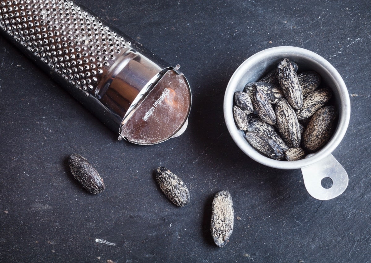 Tonkabohne und Reibe liegen auf einem Tisch.