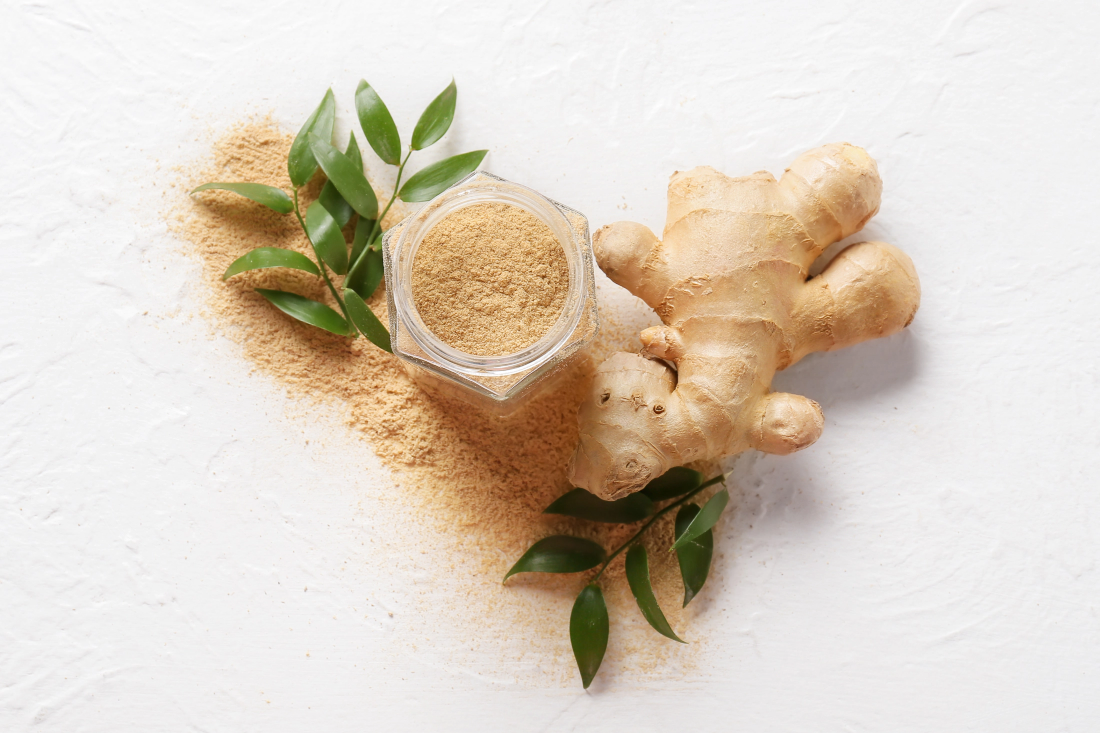 Ingwerknolle und Ingwerpulver in einem Glas.
