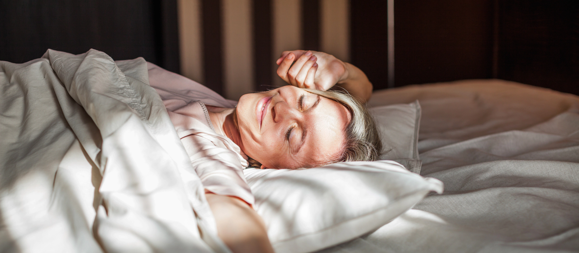 Frau schläft zufrieden in einem Bett.