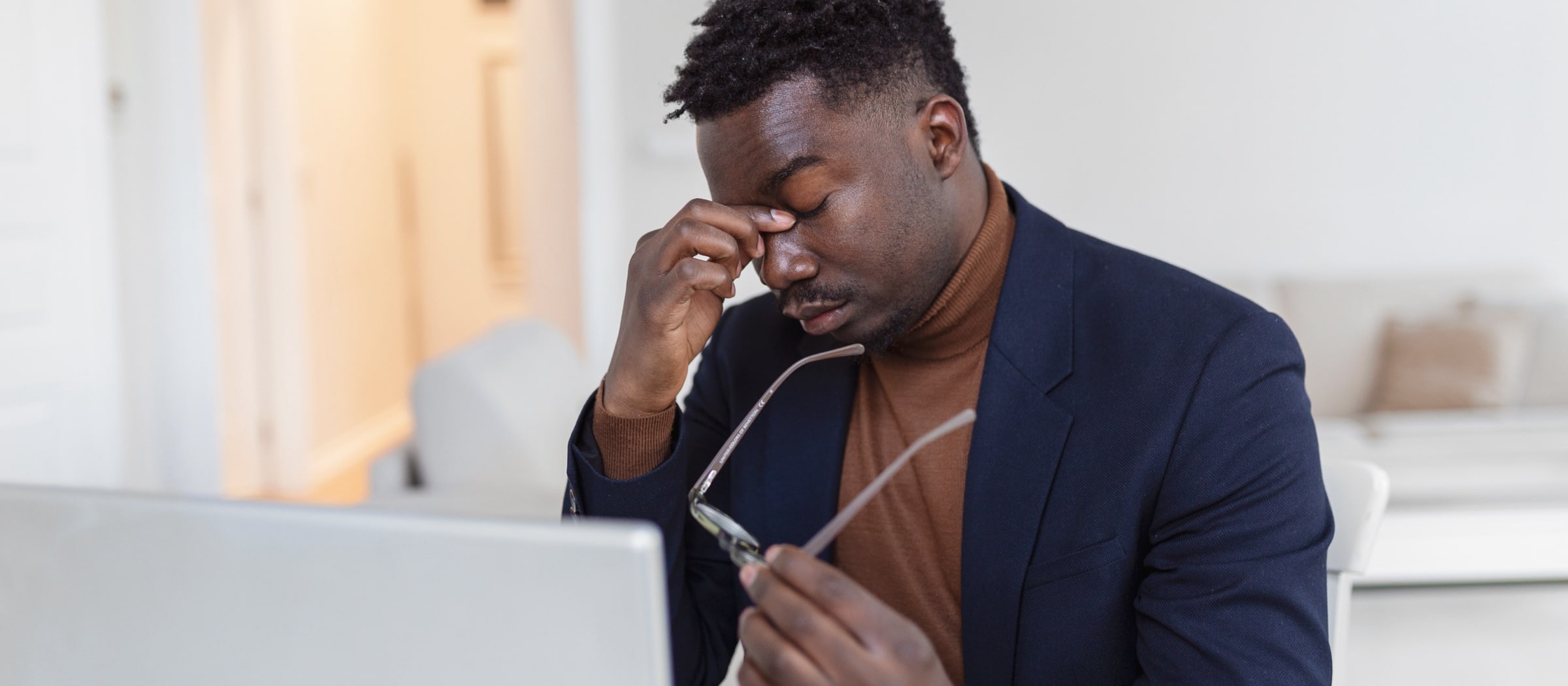 Mann sitzt vor einem Computer und reibt sich die Augen.