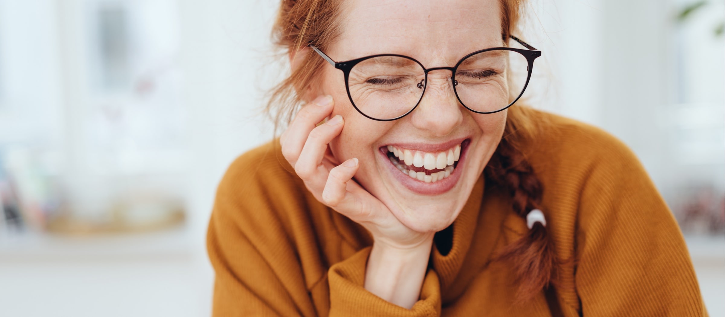 Junge Frau mit Brille lacht.