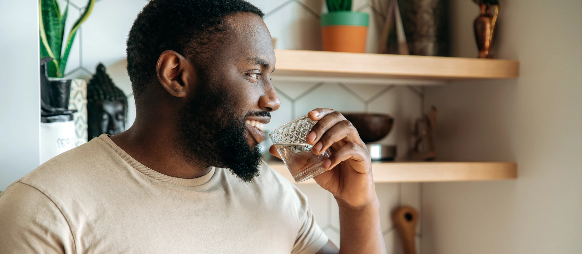Mann trinkt aus einem Glas Wasser.