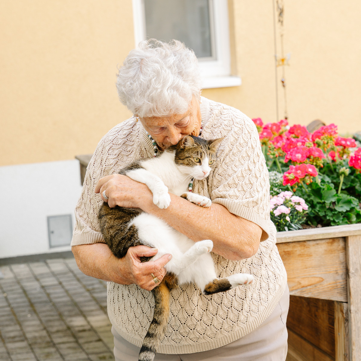 Eine Bewohnerin kuschelt mit der Hauskatze im Garten