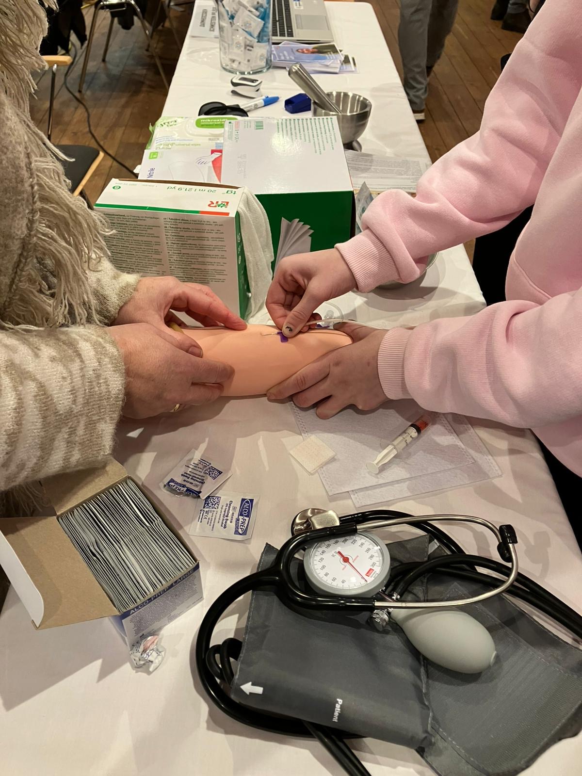 Schüler*innen probieren sich beim Blutabnehmen