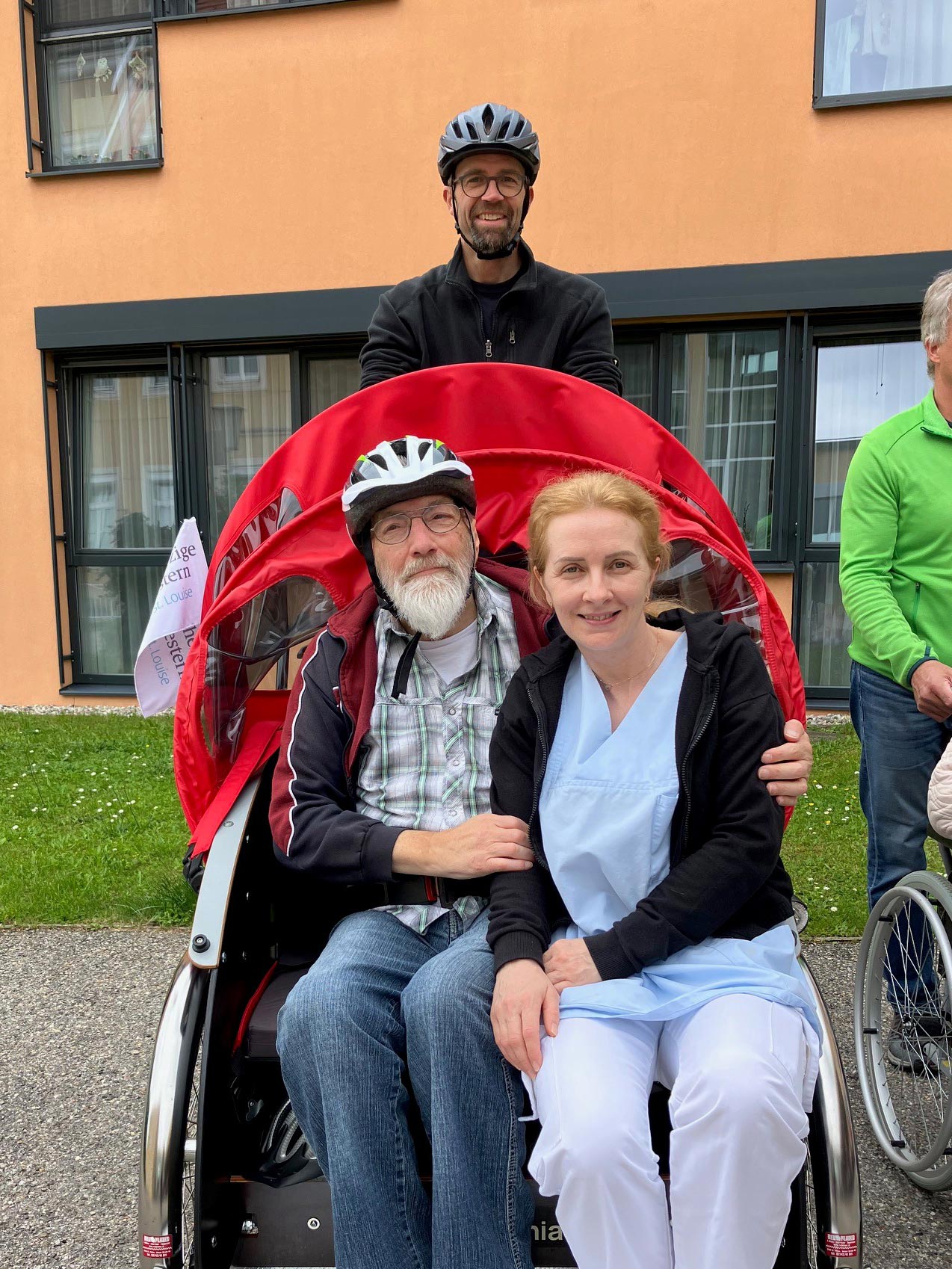 Ein ehrenamtlicher Mitarbeiter kutschiert einen Bewohner und eine Pflegekraft mit der E-Bike-Rikscha