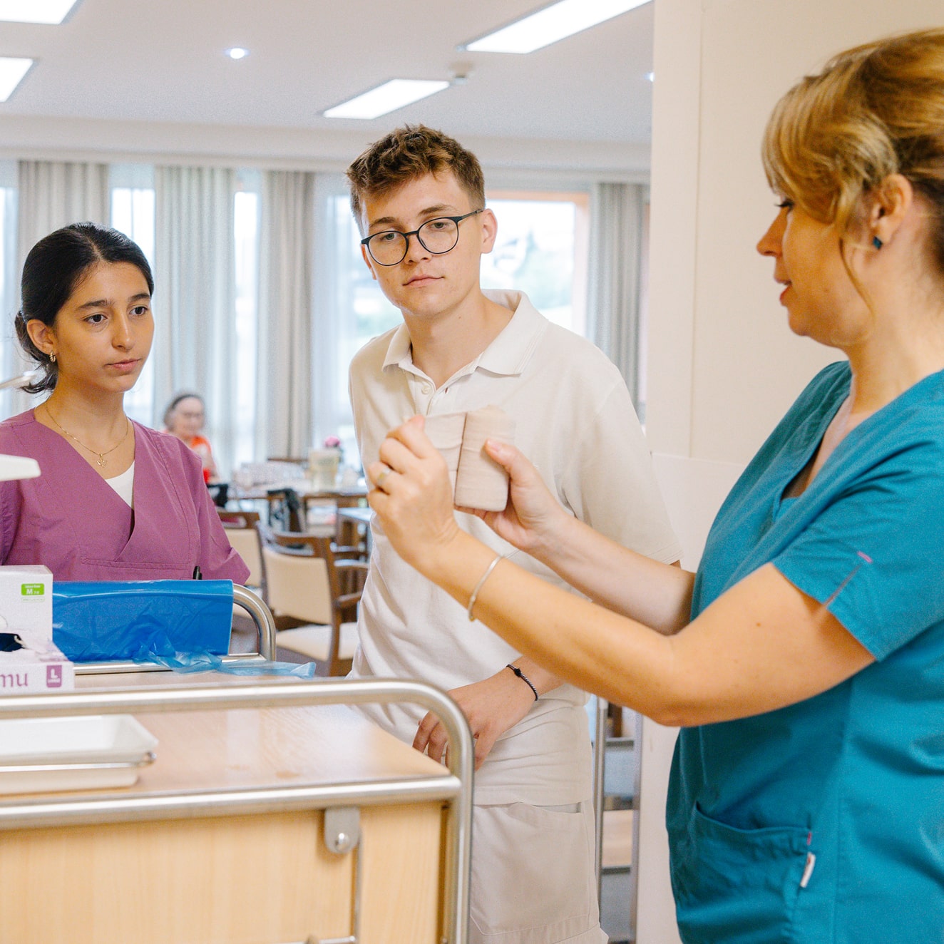 Eine erfahrene Pflegekraft schult zwei Pflegelehrlinge