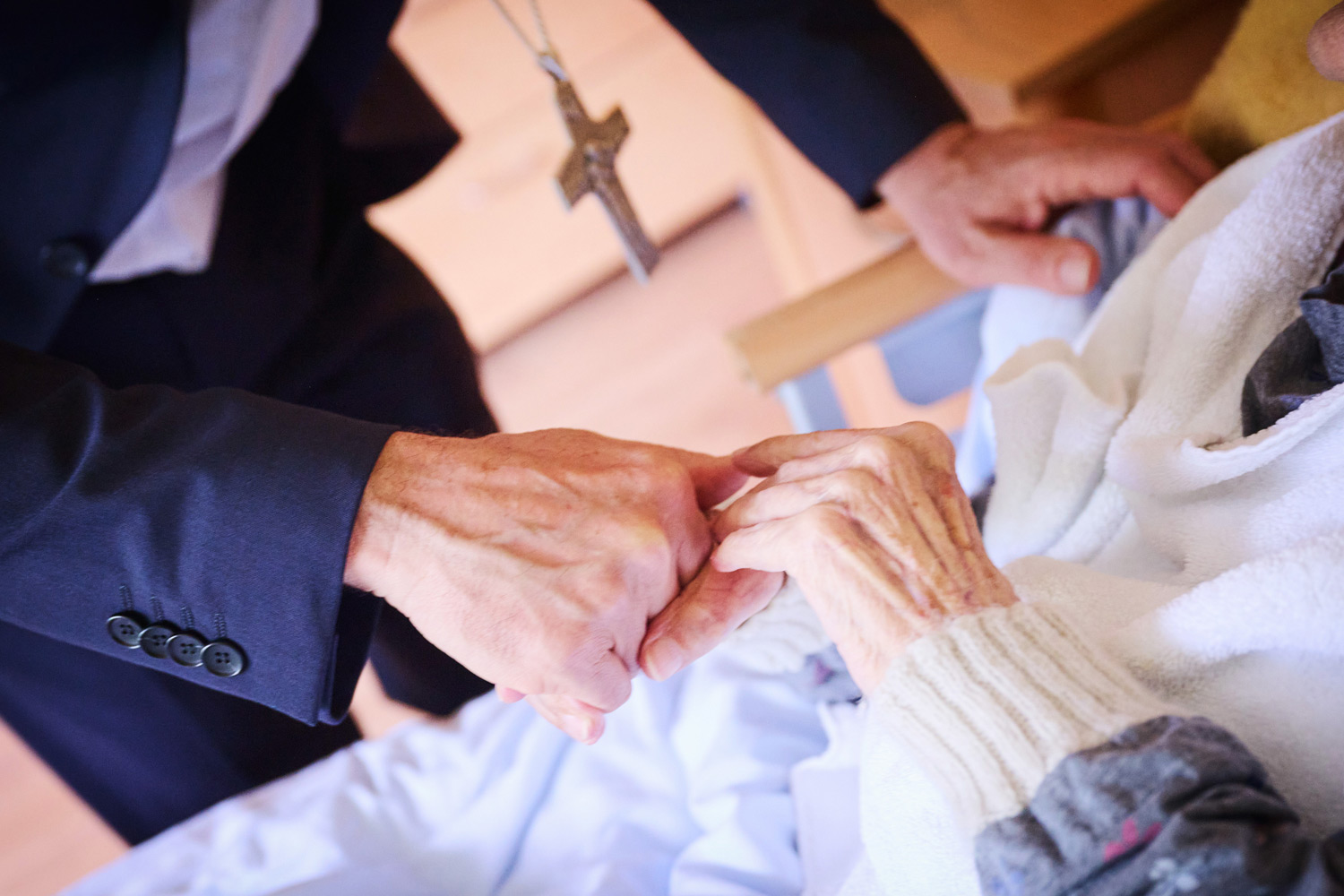 Die Hand von Erzbischof Josef Gründwidl mit der Hand einer alten Frau