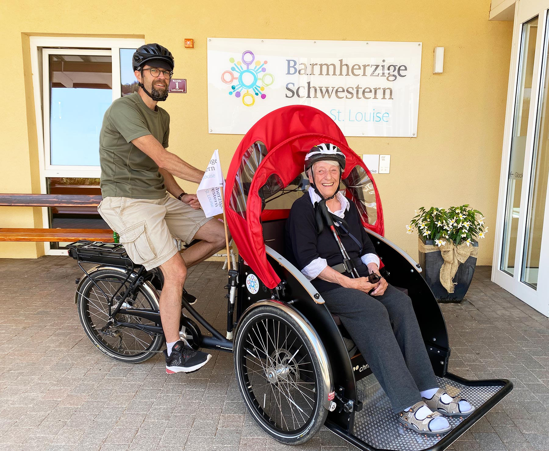 Ein Ehrenamtlicher fährt mit einer Bewohnerin mit der E-Bike-Rikscha.