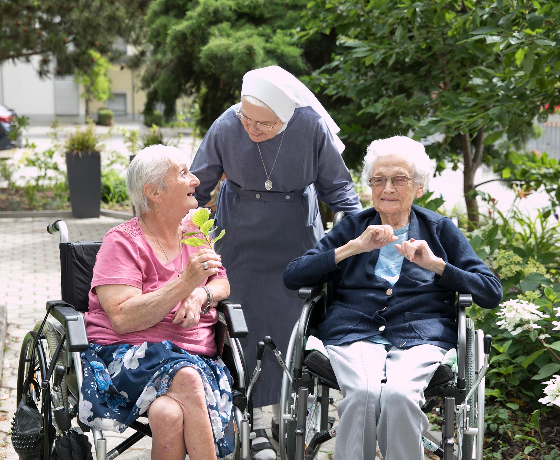 Schwester Angelina von den Barmherzigen Schwestern unterhält sich mit zwei Bewohnerinnen im Garten