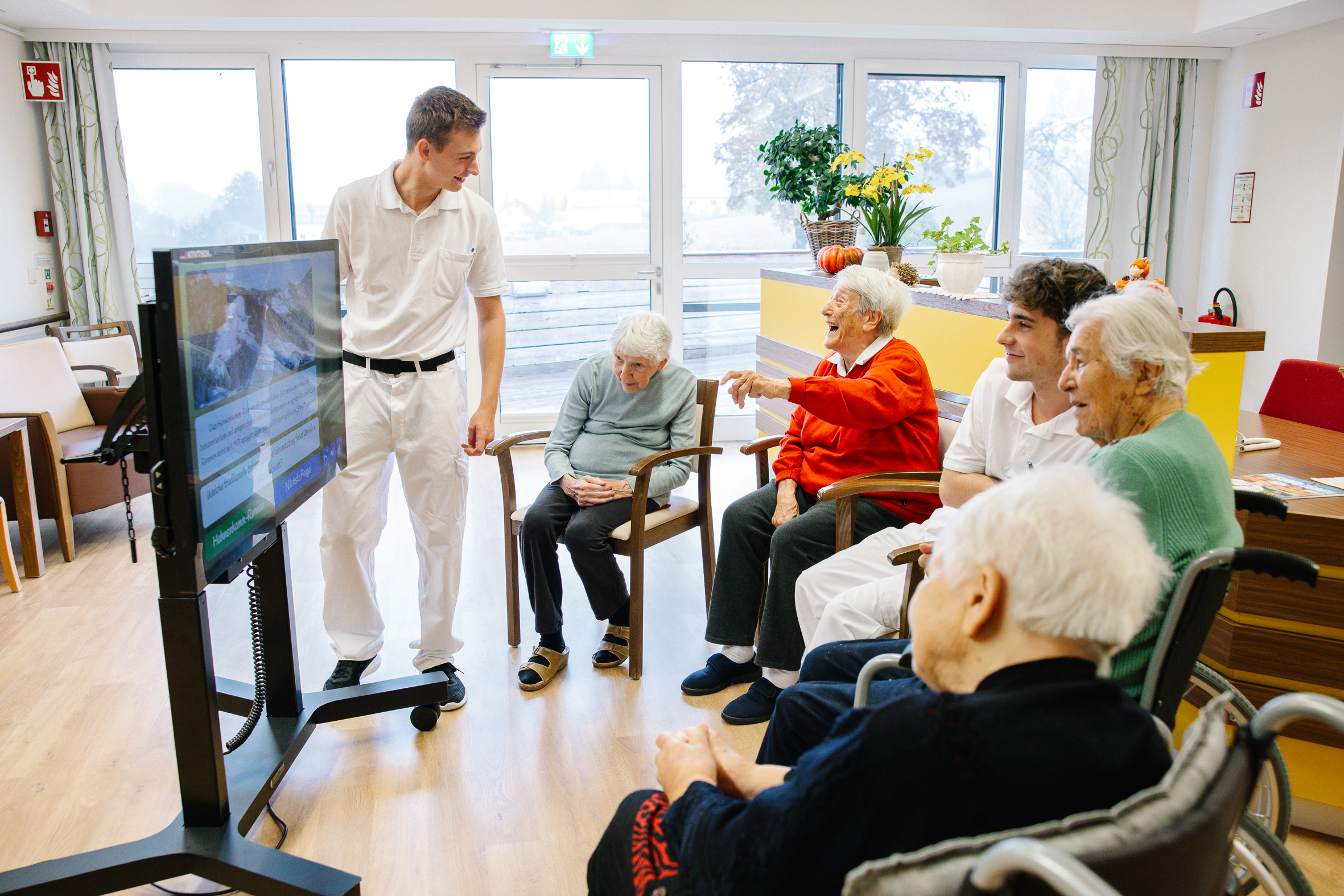 Einige Bewohnerinnen sitzen rund um den digitalen Aktivtisch und machen ein Quiz zusammen mit zweiZivildienern