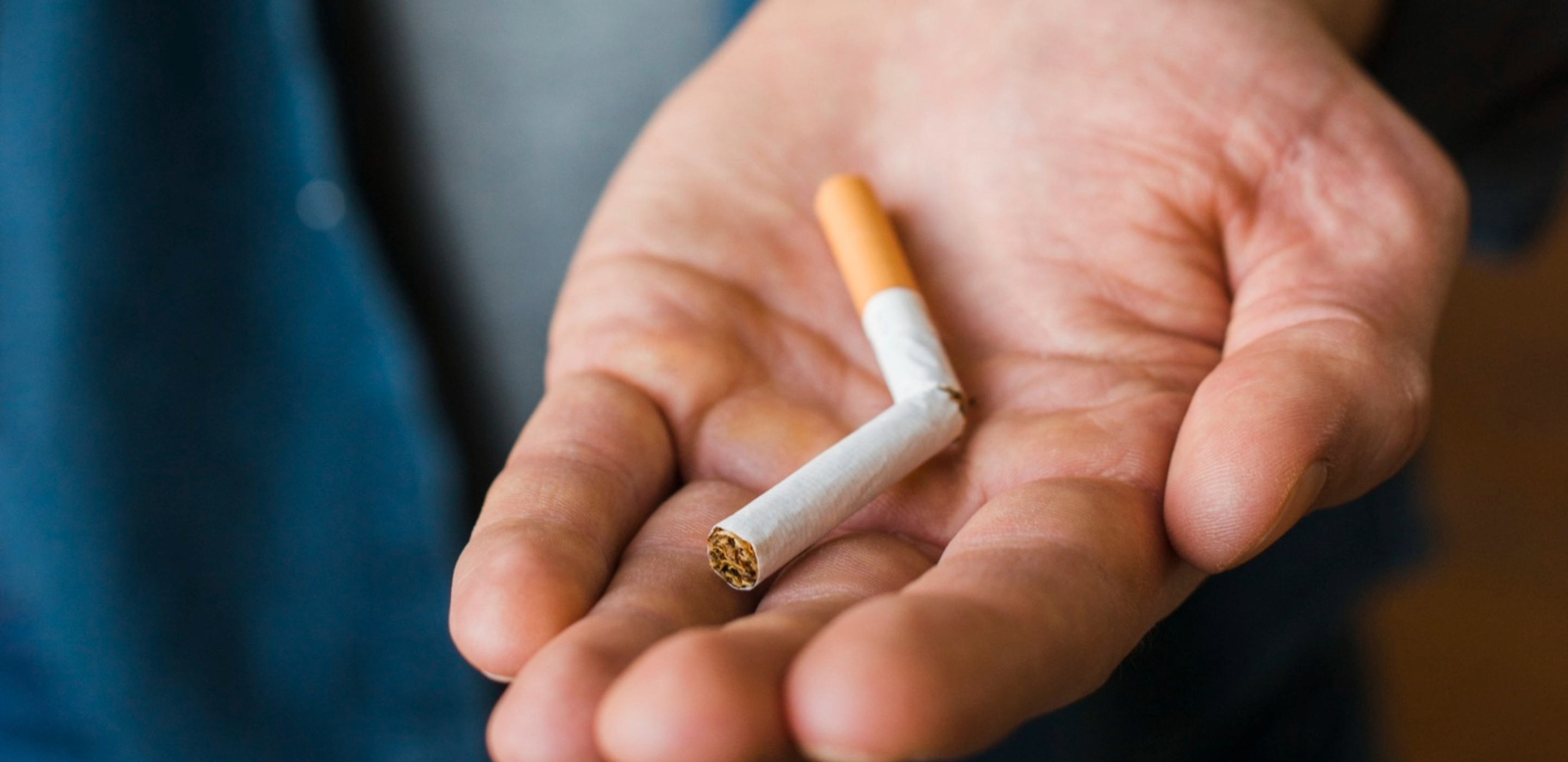 Eine Hand hält eine in der Mitte auseinander gebrochene Zigarette