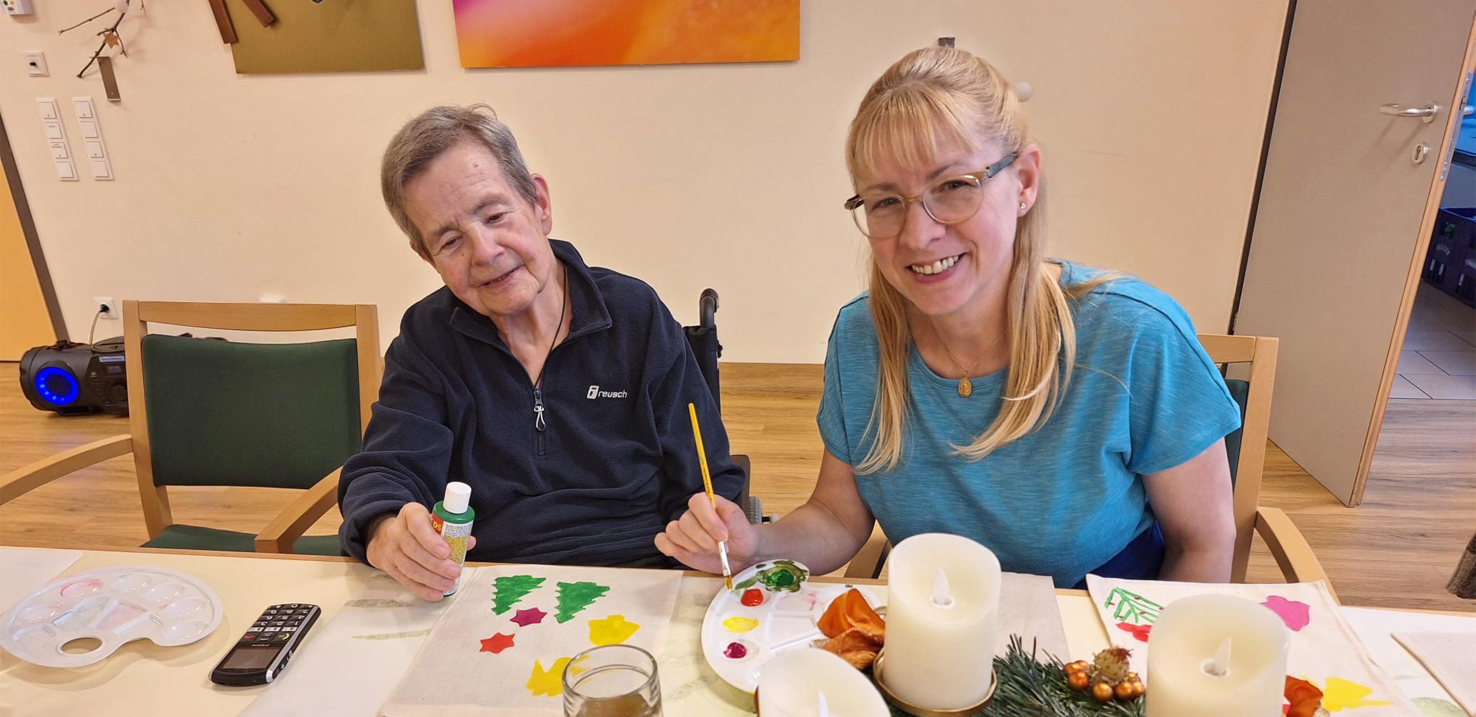 Eine Bewohnerin bemalt mit einer Mitarbeiterin schöne Weihnachtssackerl.
