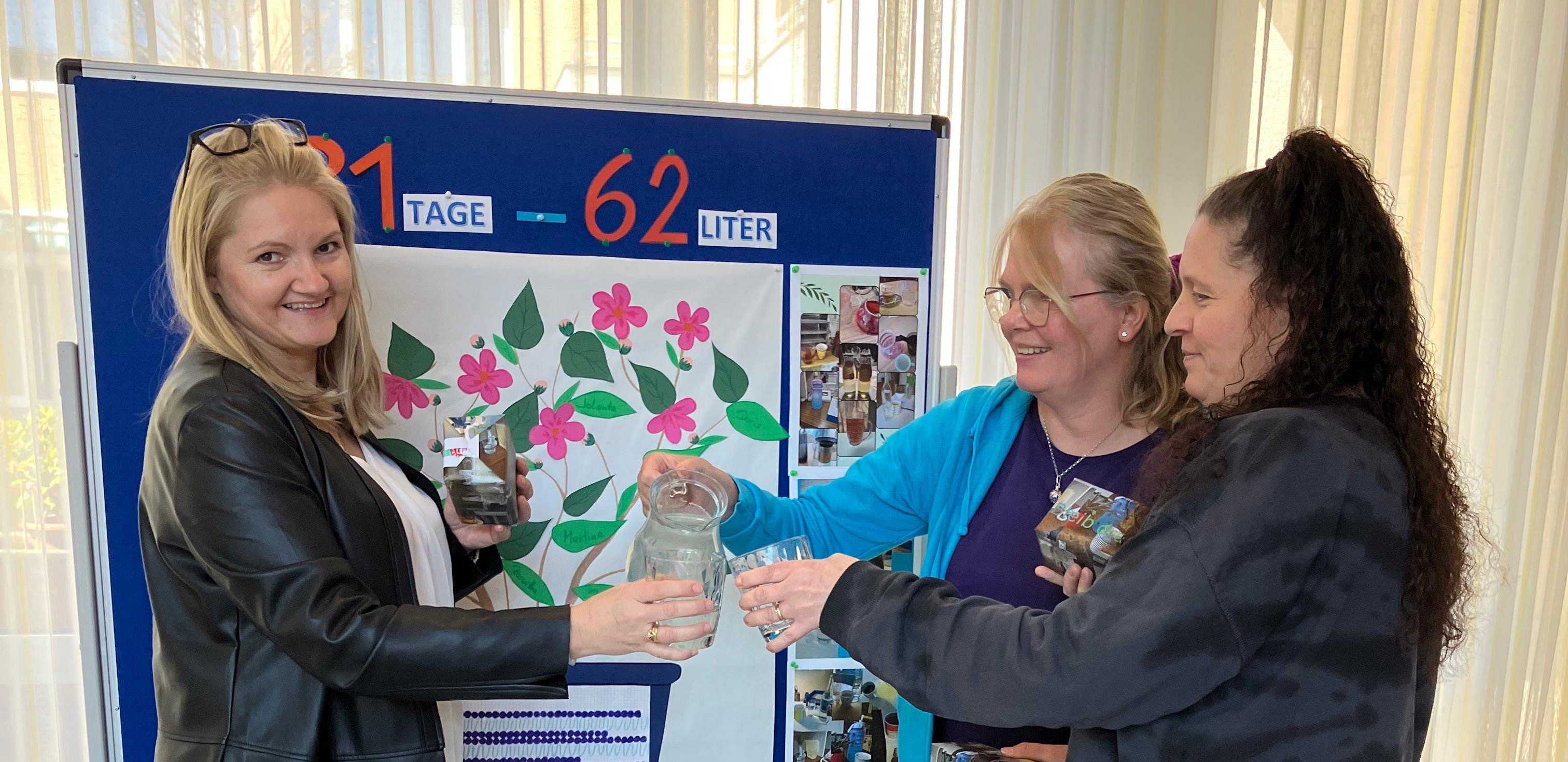 Drei Mitarbeiterinnen stoßen gemeinsam mit einem Glas Wasser an.