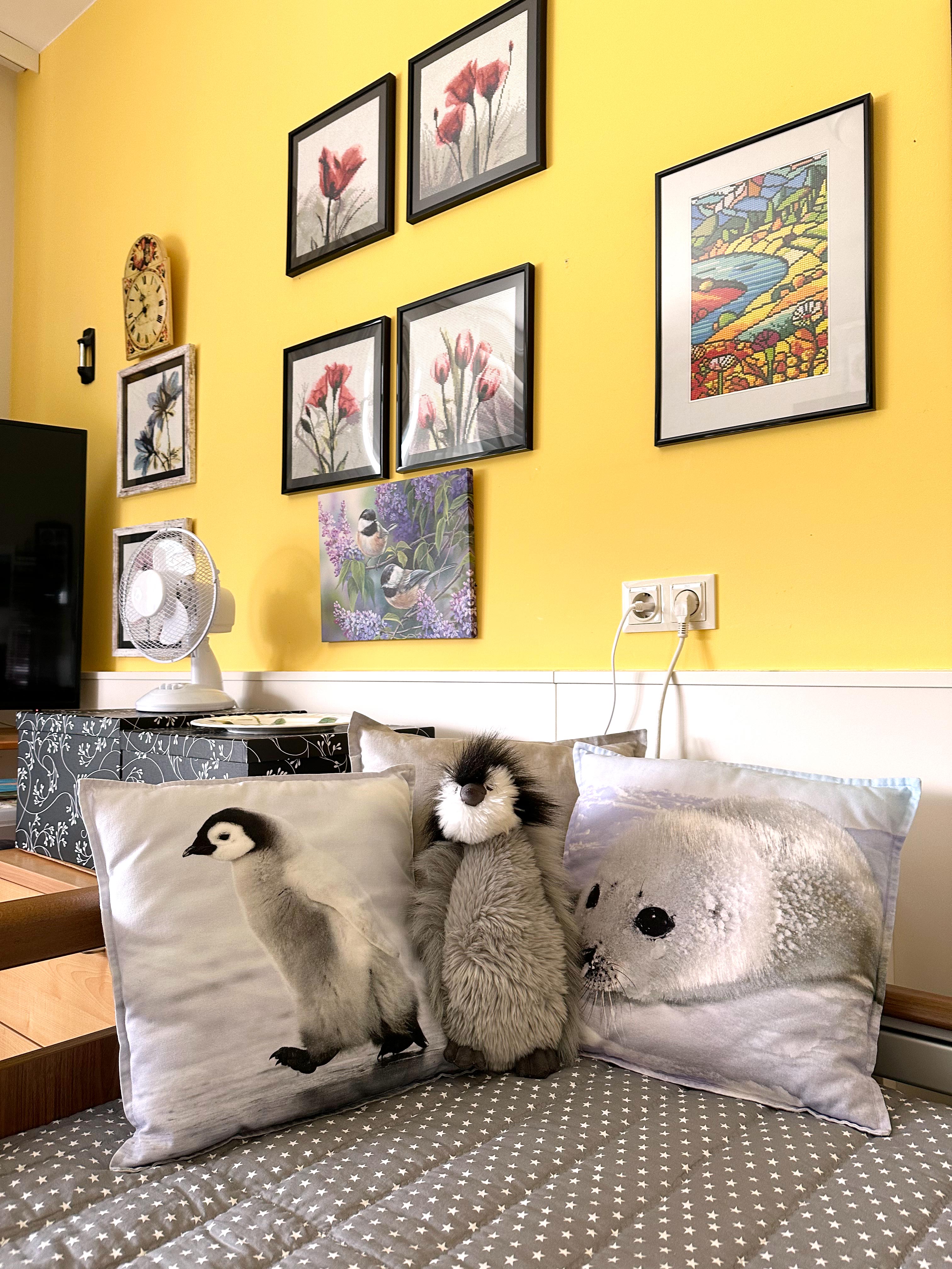 Gemütlich eingerichtetes Zimmer mit Pinguin-Pölstern und selbst gestalteten Bildern an der Wand