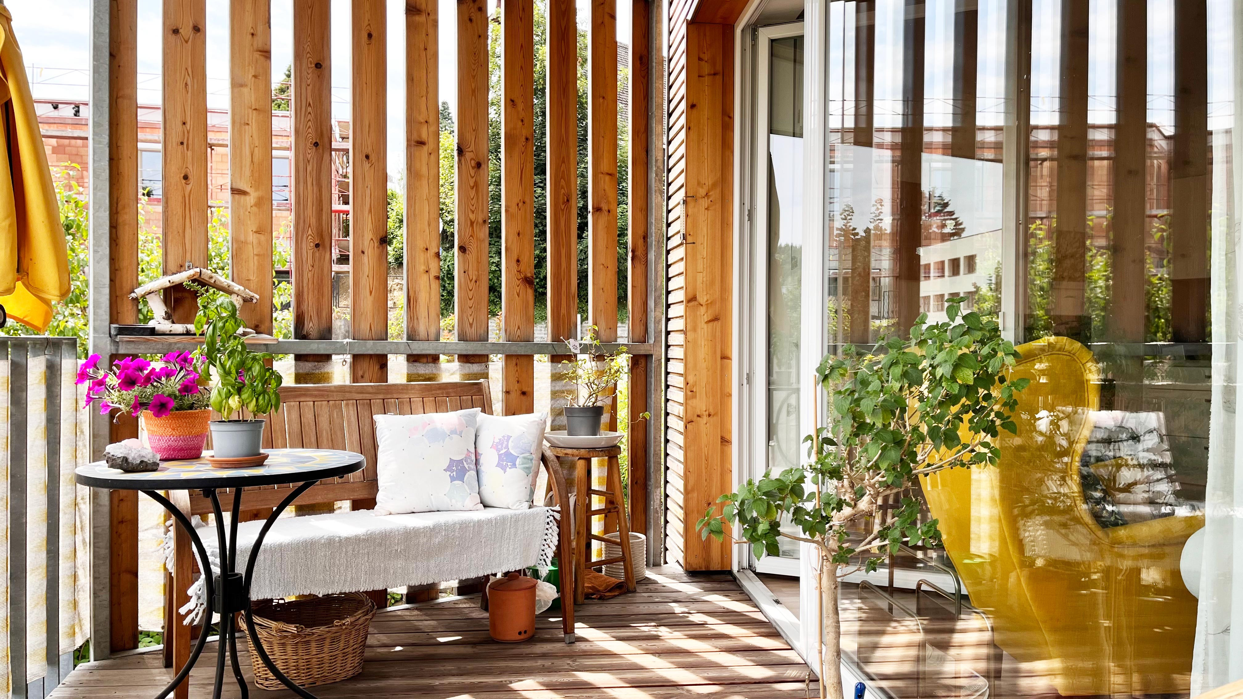 Gemütlicher Balkon mit Holzverkleidung, Sitzgelegenheiten und Pflanzen